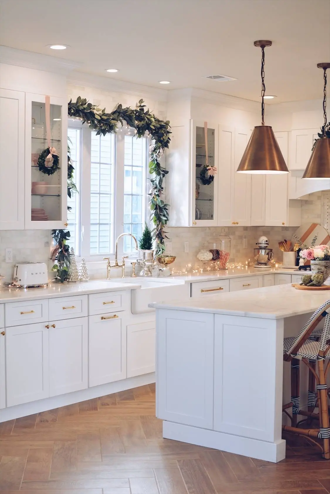White shaker kitchen with farmhouse sink and brass pendants over an island