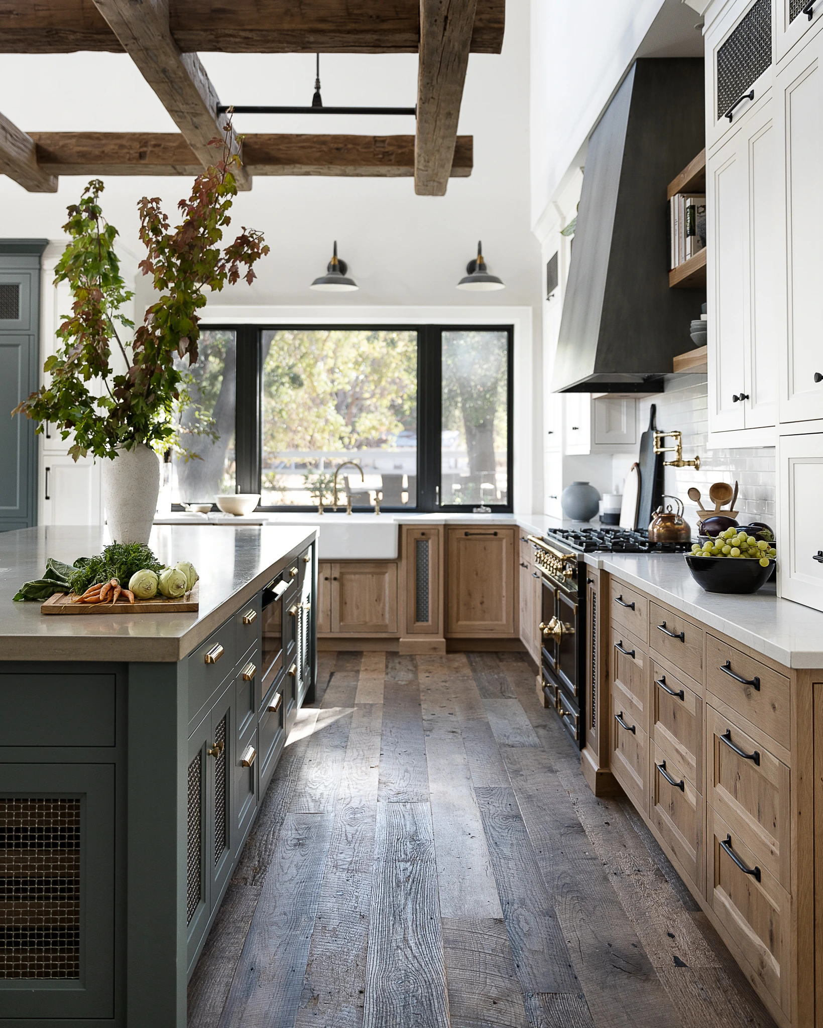 Kitchen with white oak cabinets, a green island, black range and drawer banks